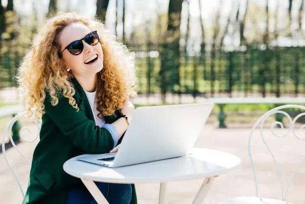 Woman sitting outside, smiling and using her laptop